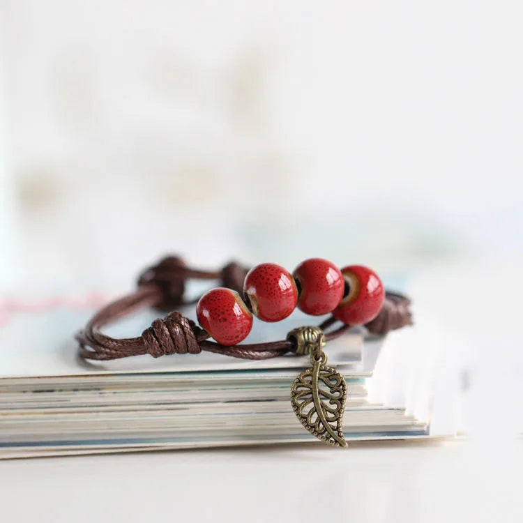 Antique-style bracelet featuring Red Color ceramic beads on a brown strand.