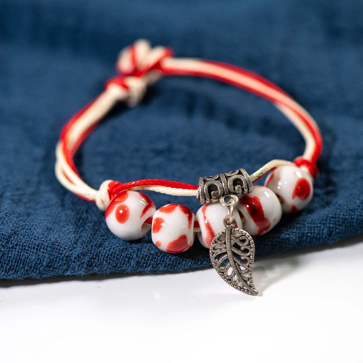 Artisan ceramic bracelet with red and white ceramic beads and intricate metalwork.