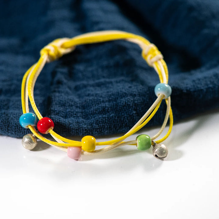 bracelet featuring multicolored ceramic beads on a yellow and white strand.