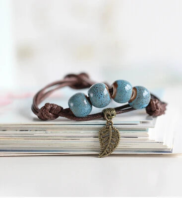 Handcrafted bracelet with ceramic blue beads and a vintage copper leaf charm.