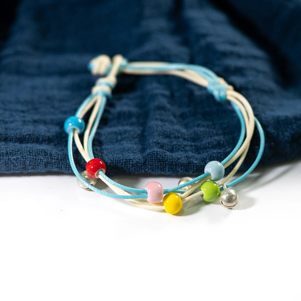 bracelet featuring multicolored ceramic beads on a blue and white strand. with a charm