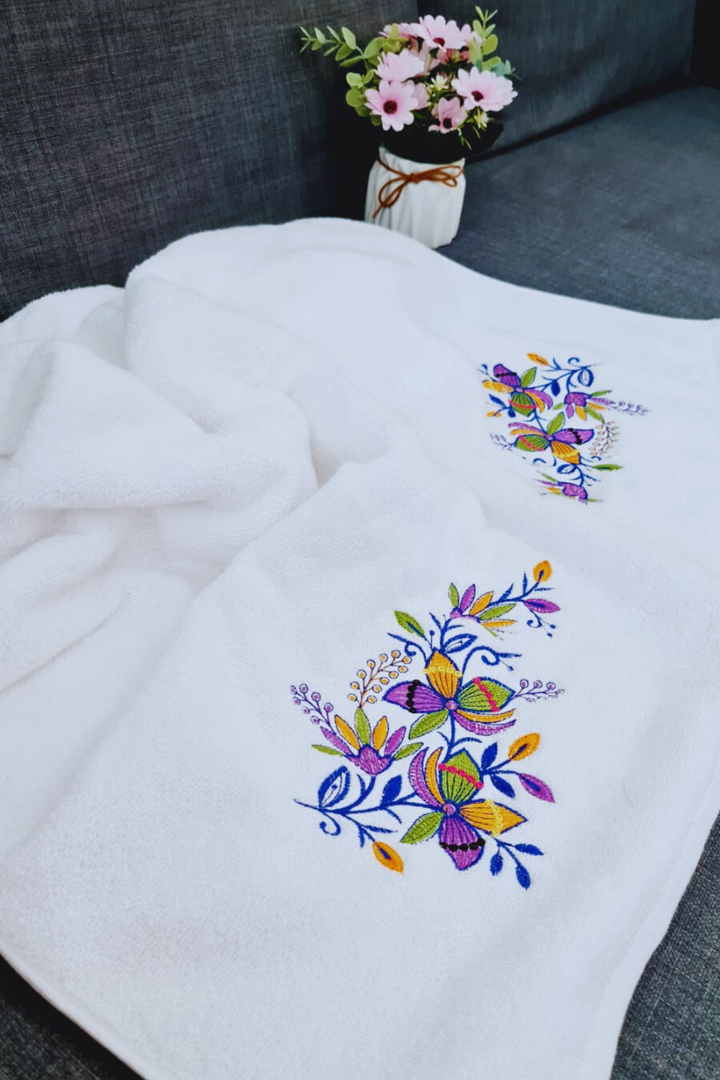 Floral embroidered bath towel displayed on a dark background, showcasing vibrant colors.