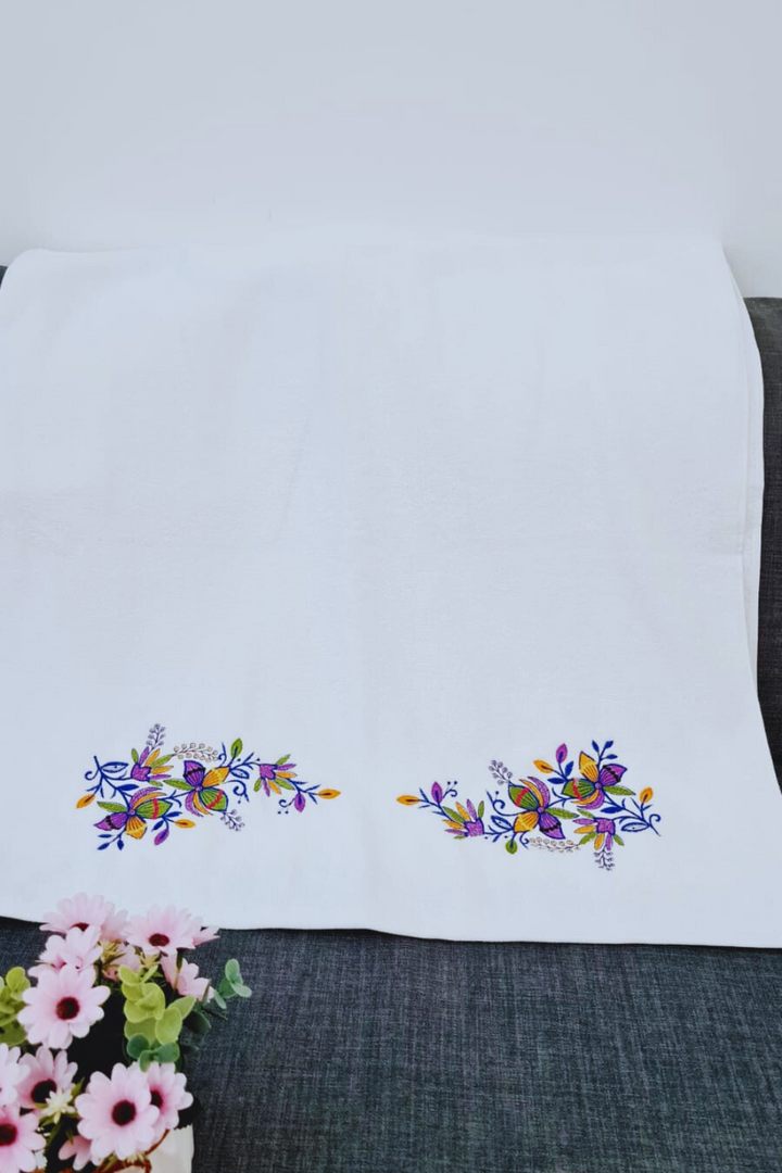 Close-up of intricate floral embroidery on a white bath towel, good quality towels in UAE.