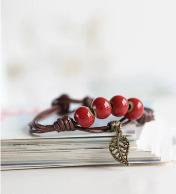 Handcrafted bracelet with ceramic red beads and a vintage copper leaf charm.