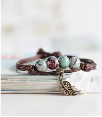 Artisan ceramic bracelet with earth-toned beads and intricate metalwork.